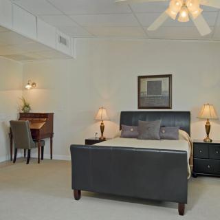 A cozy and elegantly furnished bedroom with a bed, nightstands, lamps, and a writing desk.