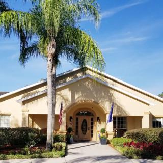 A sunny view of a building entrance with palm trees and well-maintained landscaping.