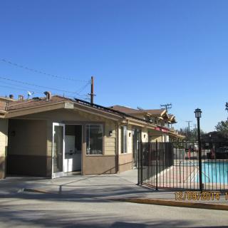 A small building next to a fenced outdoor pool under a clear blue sky.