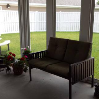 A cozy outdoor patio with a loveseat and potted plants.