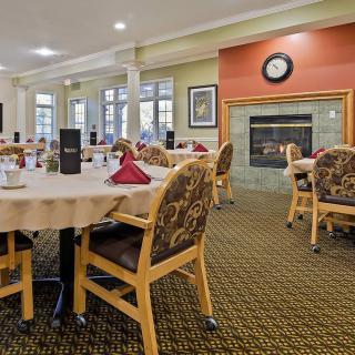 A spacious dining room with neatly arranged tables and chairs, featuring a fireplace and decorative elements.