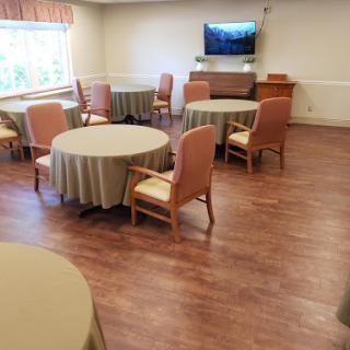 A spacious dining area featuring round tables and comfortable chairs, designed for communal gatherings.