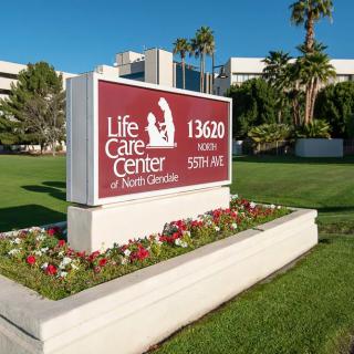 A sign for the Life Care Center of North Glendale surrounded by well-maintained landscaping.