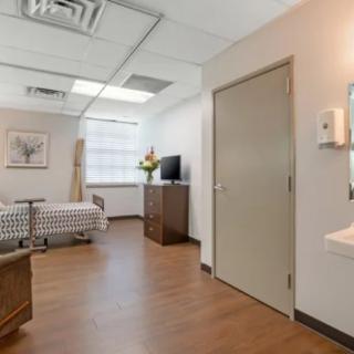 A clean and modern hospital room with a bed and television.