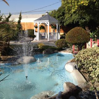 A serene garden featuring a picturesque pond with a fountain and a charming gazebo.