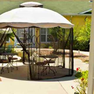 An outdoor patio area featuring a gazebo with furniture and an umbrella.