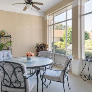 A bright and airy patio with a round table and chairs, surrounded by large windows and decorated with plants.