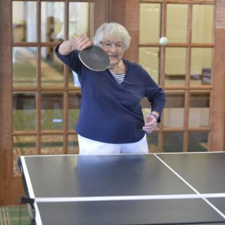 An older woman gearing up to play table tennis.