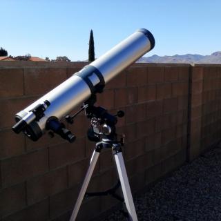 A telescope set up outdoors on a clear day, ready for stargazing.