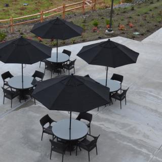 An outdoor seating area with tables, chairs, and umbrellas on a concrete patio.