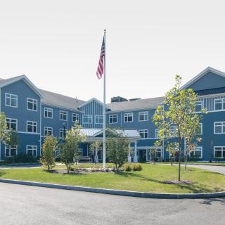 A multi-story residential building with a flagpole and landscaped surroundings.
