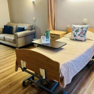 A well-furnished hospital room with a bed and a sofa, featuring a clean and accessible environment.