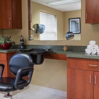 A hair salon interior with a styling chair, mirror, and countertop with folded towels.