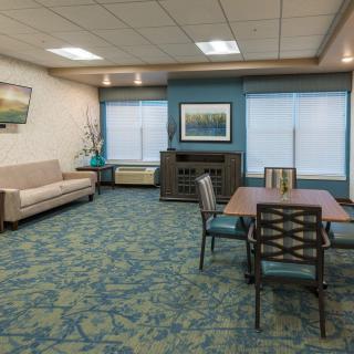 A spacious waiting room with a sofa, table, chairs, and decorative artwork.