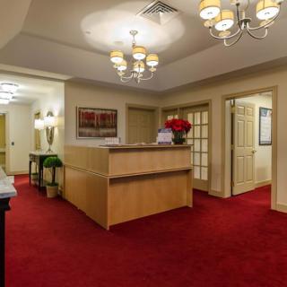 A well-lit office reception area with red carpeting and elegant chandeliers.