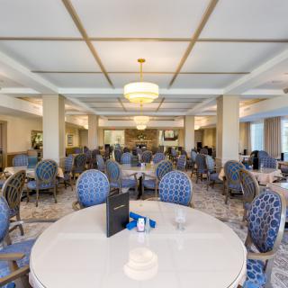 An elegantly decorated dining area with multiple tables and chairs arranged in a spacious, well-lit room.