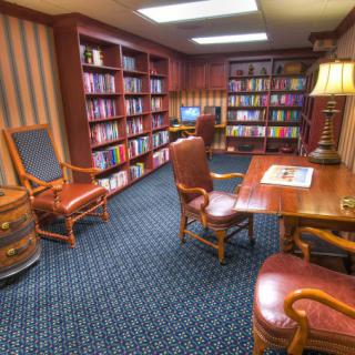 A cozy library room with bookshelves, a reading desk, and comfortable chairs.