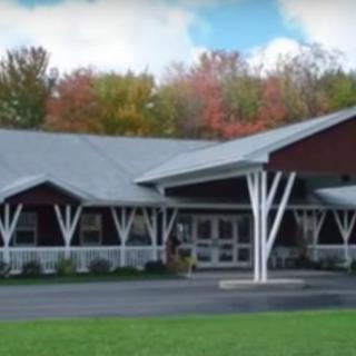 A modern building with a pitched roof surrounded by autumn foliage.