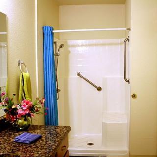 A bathroom interior featuring a shower with a blue curtain and grab bar.