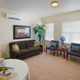 A cozy living room with a sofa, two chairs, a coffee table, and decor including plants and artwork.