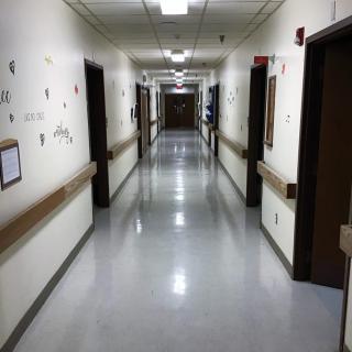 A quiet hospital corridor with rooms along both sides.