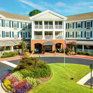 A well-maintained residential building with a landscaped entrance and vibrant flowerbeds under a clear sky.