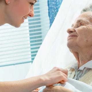 A nurse cares for an elderly patient in a hospital setting.