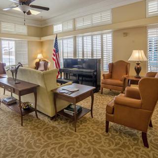 A spacious living room featuring cozy furniture, a television, and large windows with an American flag in the corner.