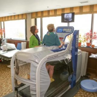 A person using an anti-gravity treadmill under the supervision of a therapist in a rehabilitation clinic.