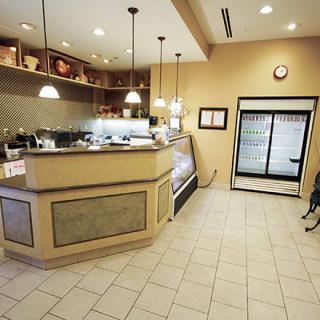 An empty coffee shop interior with a counter, display case, and refrigerator.