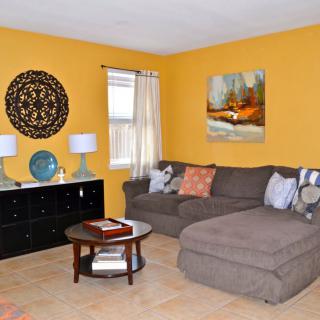 A cozy living room with yellow walls, featuring a brown sectional sofa, a round coffee table, and various decorative elements.