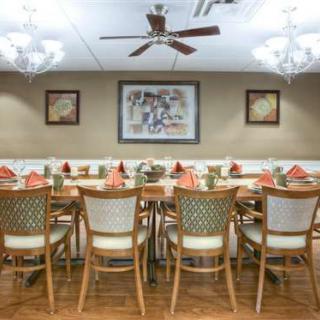A well-arranged dining room with a long table set for a meal, featuring elegant decor and lighting.