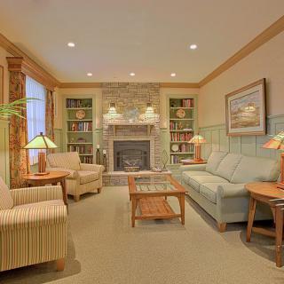 A cozy living room features a stone fireplace, surrounded by comfortable seating and warm lighting.