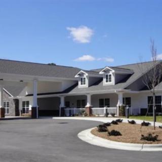 A large residential building with a circular driveway and landscaped surroundings.