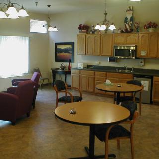 A cozy kitchen and dining area with wooden cabinets, tables, and comfortable seating.