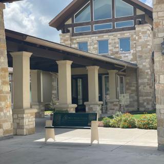 A building with a stone facade, featuring an entrance with columns and a covered walkway.