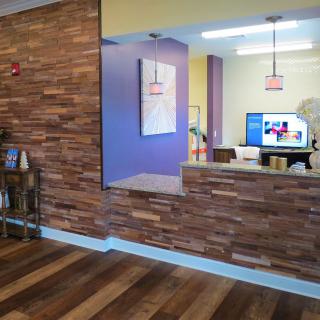 A modern reception area featuring a wooden accent wall and a sleek desk, showcasing contemporary interior design elements.