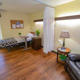 A cozy hospital room with a bed, seating area, and decorative elements.