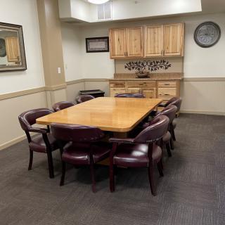 A spacious conference room with a large wooden table and leather chairs, ideal for meetings.