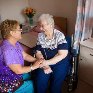A caregiver lovingly interacts with an elderly woman in a hospital room, highlighting the importance of compassion and support in healthcare.