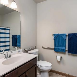 A neatly organized bathroom featuring a sink, toilet, and blue towels.