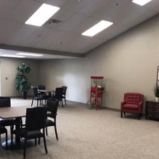 A spacious office area with tables and chairs, featuring a popcorn machine and a red armchair.