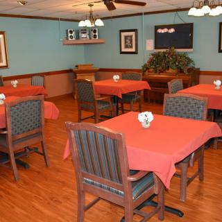 An empty dining area with tables covered in red tablecloths.