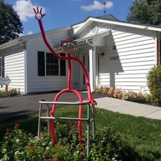 A playful red sculpture welcoming visitors outside a white building.