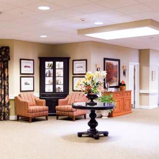 A well-designed lobby area featuring comfortable seating, decorative artwork, and a central table with a flower arrangement.