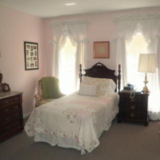 A traditional bedroom with a single bed, dresser, and nightstand.