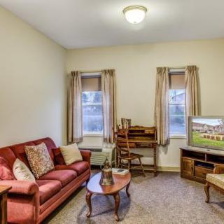 A cozy living room with a red sofa, coffee table, TV, and curtains.