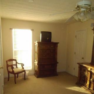 A sunlit room with antique furniture including a chair and dresser.