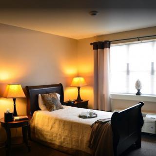 A cozy bedroom with a single bed and warm lighting.