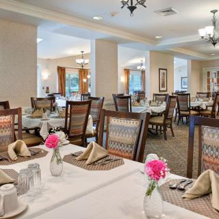 A well-decorated dining area featuring tables with floral centerpieces and neatly arranged table settings.